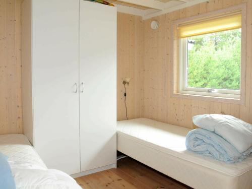 OksbølにあるThree-Bedroom Holiday home in Oksbøl 17の窓とベッド付きの小さなベッドルーム1室が備わります。