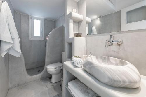 a white bathroom with a sink and a toilet at Aegean Dream Apartments in Tinos