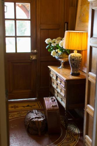 a room with a table with a lamp and a vase of flowers at Knockderry Country House Hotel in Cove