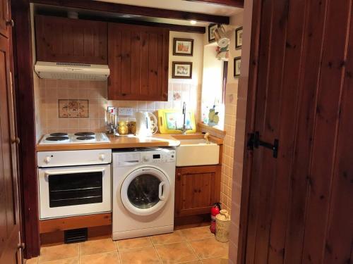 een keuken met een wasmachine en een fornuis bij Cosy Cottage for Ecotourism lovers near Corwen in Corwen