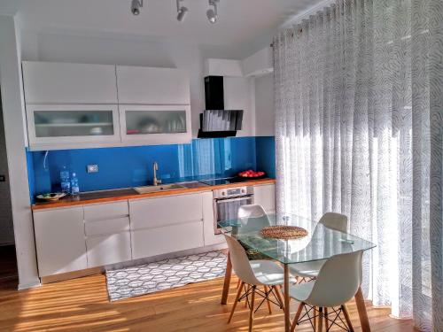d'une cuisine avec une table et des chaises en verre et des murs bleus. dans l'établissement Oslo Apartments - Albania, à Vlorë