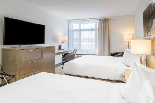a hotel room with two beds and a flat screen tv at Repotel Aéroport Québec in Quebec City