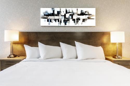 a bedroom with a white bed with two lamps at Repotel Aéroport Québec in Quebec City