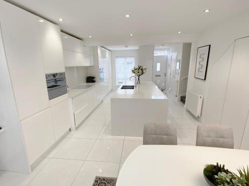 a kitchen with white cabinets and a table and chairs at Summer House Terrace in Yeovil