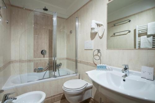 a bathroom with a tub and a toilet and a sink at Hotel Kennedy in Rome