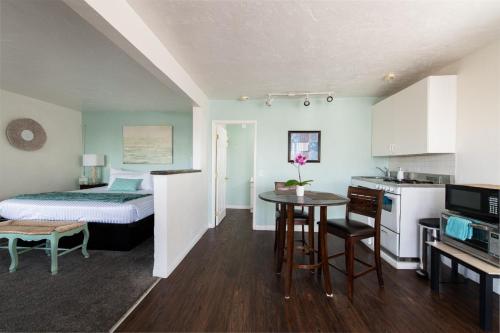 a room with a bed and a kitchen with a table at The Patriots Boutique Motel in San Clemente