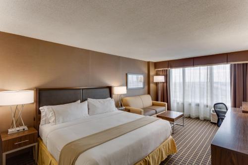a hotel room with a large bed and a chair at Holiday Inn Express Washington DC SW - Springfield by IHG in Springfield