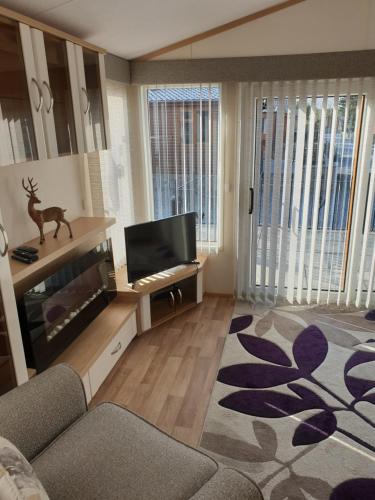 een woonkamer met een bank en een flatscreen-tv bij Deer lodge in Auchterarder