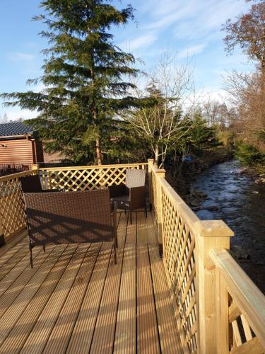 a wooden deck with two benches and a table on it at Deer lodge in Auchterarder