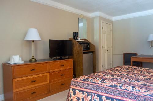 a bedroom with a bed and a dresser with a television at America's Inn Houston in Houston