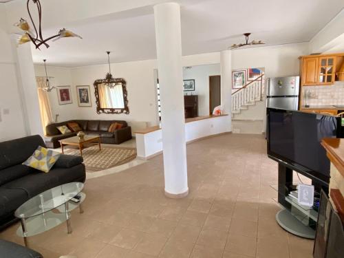a living room with a couch and a tv at 6 bdr villa with TENNIS COURT in Paphos
