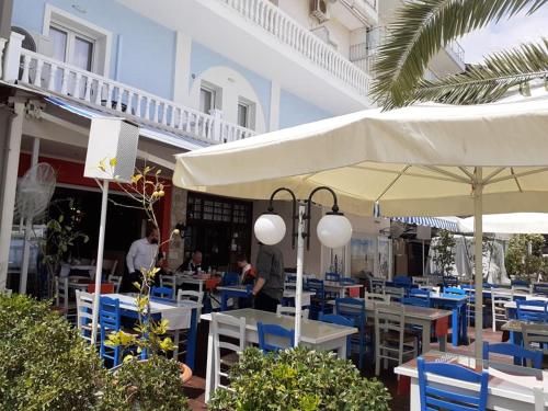 a restaurant with blue chairs and white tables and umbrellas at Hotel Zografos in Paralia Katerinis