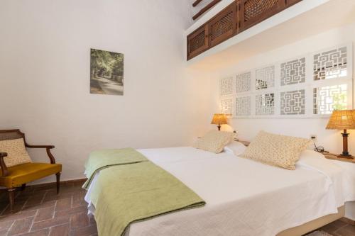 um quarto com uma cama branca e uma cadeira amarela em Quinta do Caracol em Tavira