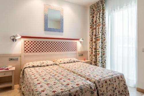 a bedroom with a bed and a mirror and a window at Hotel Katja in Bibione