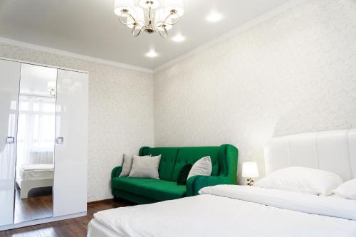 カリーニングラードにあるApartment Elegantの緑のソファと鏡が備わるベッドルーム1室