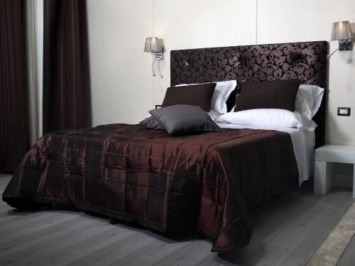 een slaapkamer met een bed met een bruine deken en kussens bij Piccolo di Piazza di Spagna Suites in Rome