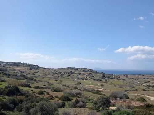 a view of a hill with the ocean in the background at PANORAMA in Pitsidia