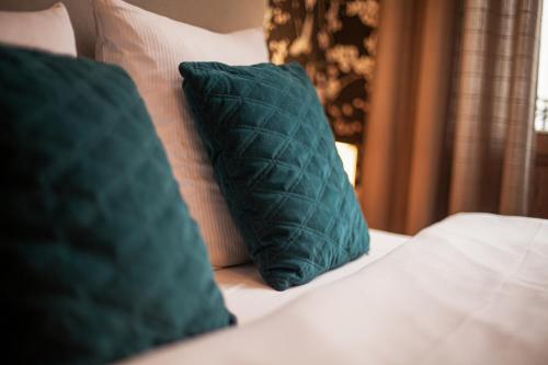 two green pillows are sitting on a bed at Luxury Suites Historic Center by Rikas Hotels in Antwerp