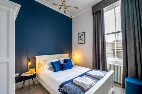 a bedroom with a bed with blue walls and a window at 5 Rowntree House in York