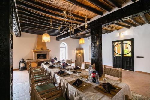 a dining room with tables and chairs and a fireplace at Kasbah Mohayut in Merzouga