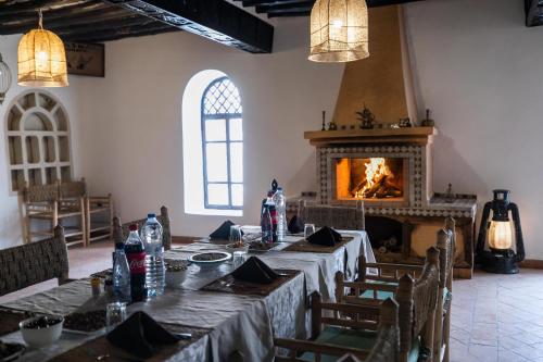 a dining room with a table and a fireplace at Kasbah Mohayut in Merzouga