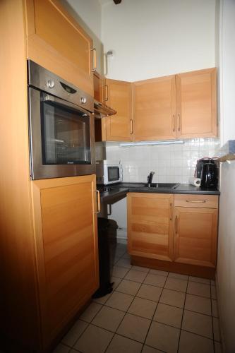 Elle comprend une petite cuisine avec des placards en bois et un évier. dans l'établissement La Chambre d'Emma, à Dieppe