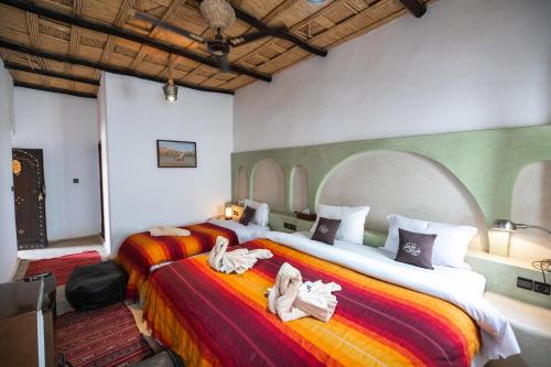 two beds in a room with towels on them at Kasbah Mohayut in Merzouga