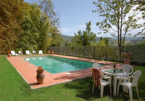 a swimming pool with a table and chairs next to it at Villa Di Collina in Vicchio