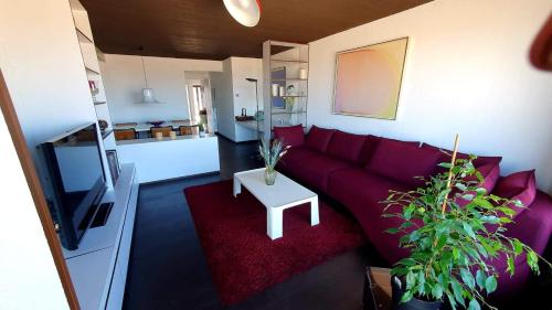 a living room with a purple couch and a table at Modern appartement met frontaal zeezicht en privé parking in Knokke-Heist