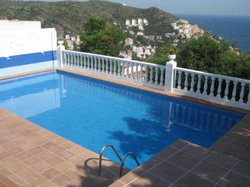 a swimming pool with a white fence and the ocean at Villa Buraux III in Roses