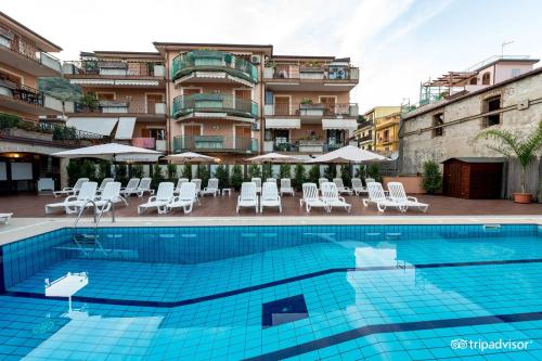 ein Pool mit Stühlen und ein Hotel in der Unterkunft Taormina Hotel Calipso in Mazzeo