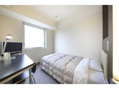 a bedroom with a bed and a desk and a window at R&B HOTEL HACHIOJI - Vacation STAY 13862v in Hachioji