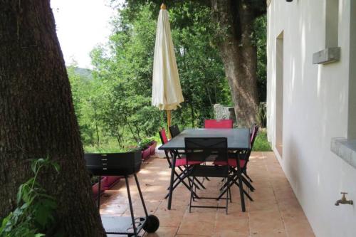 un patio avec une table et un parasol dans l'établissement Les châtaigniers du Thaurac, à Saint-Bauzille-de-Putois