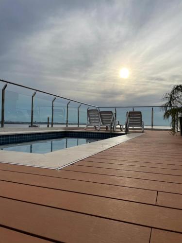 a deck with chairs and a swimming pool on a building at Monoambiente a 400 metros de la playa in Encarnación