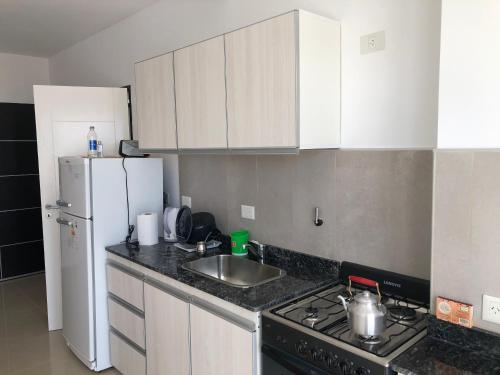 a kitchen with a sink and a stove and a refrigerator at Departamento Centrico VDL in Puerto Madryn