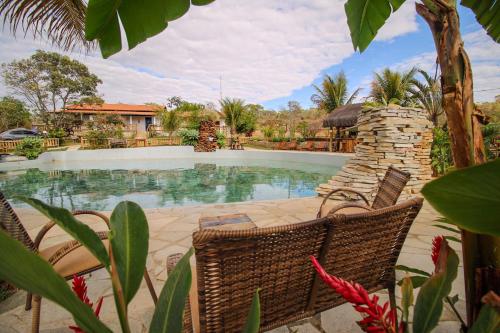 a swimming pool with chairs in front of a house at Pousada Vereda da Serra in Pirenópolis