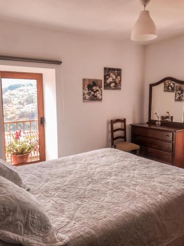 a bedroom with a bed and a dresser and a window at Casa Sambinho Gerês in Rio Caldo