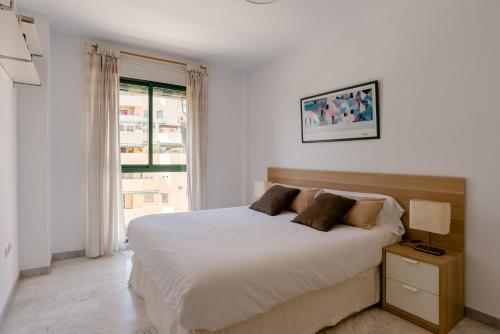 a white bedroom with a bed and a window at Apartamento Residencial Bajondillo in Torremolinos