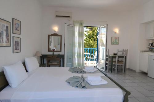 a bedroom with a large white bed and a kitchen at Astra Hotel Apartments in Kato Daratso