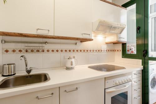 eine weiße Küche mit einer Spüle und einem Herd in der Unterkunft Apartamento Residencial Bajondillo in Torremolinos