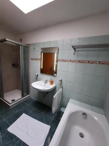 La salle de bains est pourvue d'une baignoire, d'un lavabo et d'une douche. dans l'établissement Apartment Aigner, à Bad Goisern