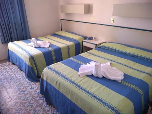 a hotel room with three beds with towels on them at HOTEL OLIDEN in Coatzacoalcos