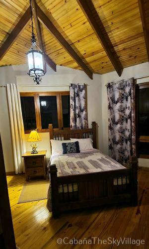 a bedroom with a bed and a lamp and windows at Villa The sky village in Jarabacoa