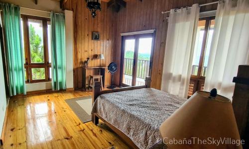 a bedroom with a bed in a room with windows at Villa The sky village in Jarabacoa