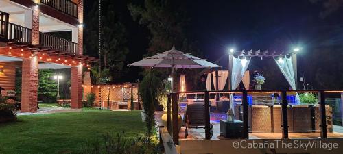 a patio with an umbrella in a yard at night at Villa The sky village in Jarabacoa