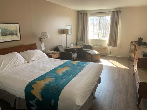 Habitación de hotel con cama y sala de estar. en Hotel Transit, en Mont-Saint-Hilaire