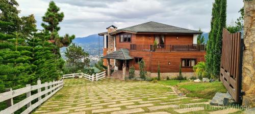 a wooden house with a fence in front of it at Villa The sky village in Jarabacoa