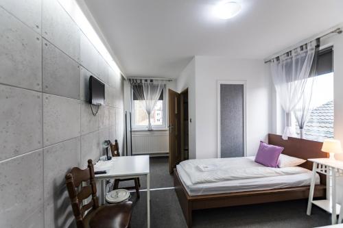 a small room with a bed and a desk and a sink at Hotel Zajazdu w Ostrzeszowie in Ostrzeszów