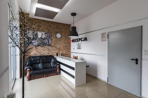 a lobby with a leather chair and a white desk at Hotel Zajazdu w Ostrzeszowie in Ostrzeszów