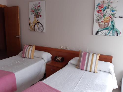 a room with two beds and a bike on the wall at Rúa A plaza la constitución 16 in Fisterra